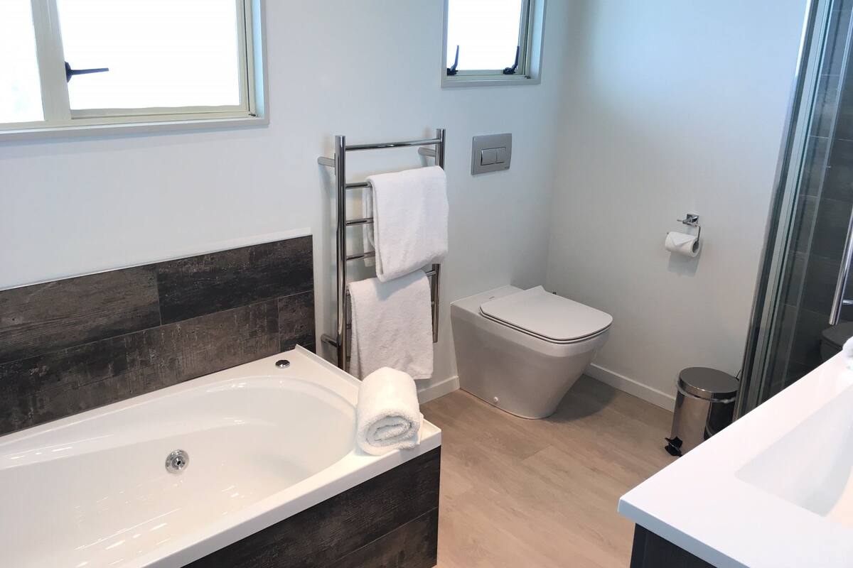 Une salle de bain moderne équipée d’une baignoire, de toilettes et d’une douche.