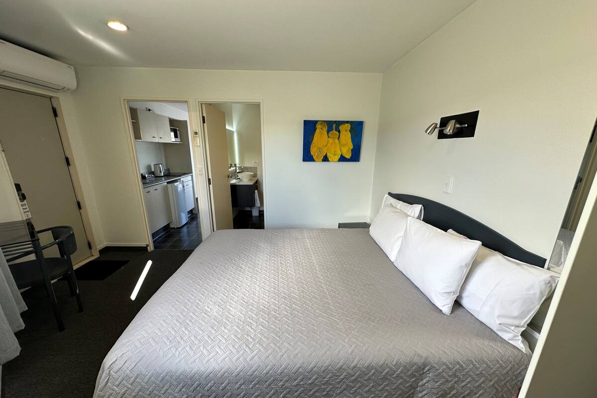 Une chambre d’hôtel avec un lit, un bureau et une kitchenette à l’arrière-plan.