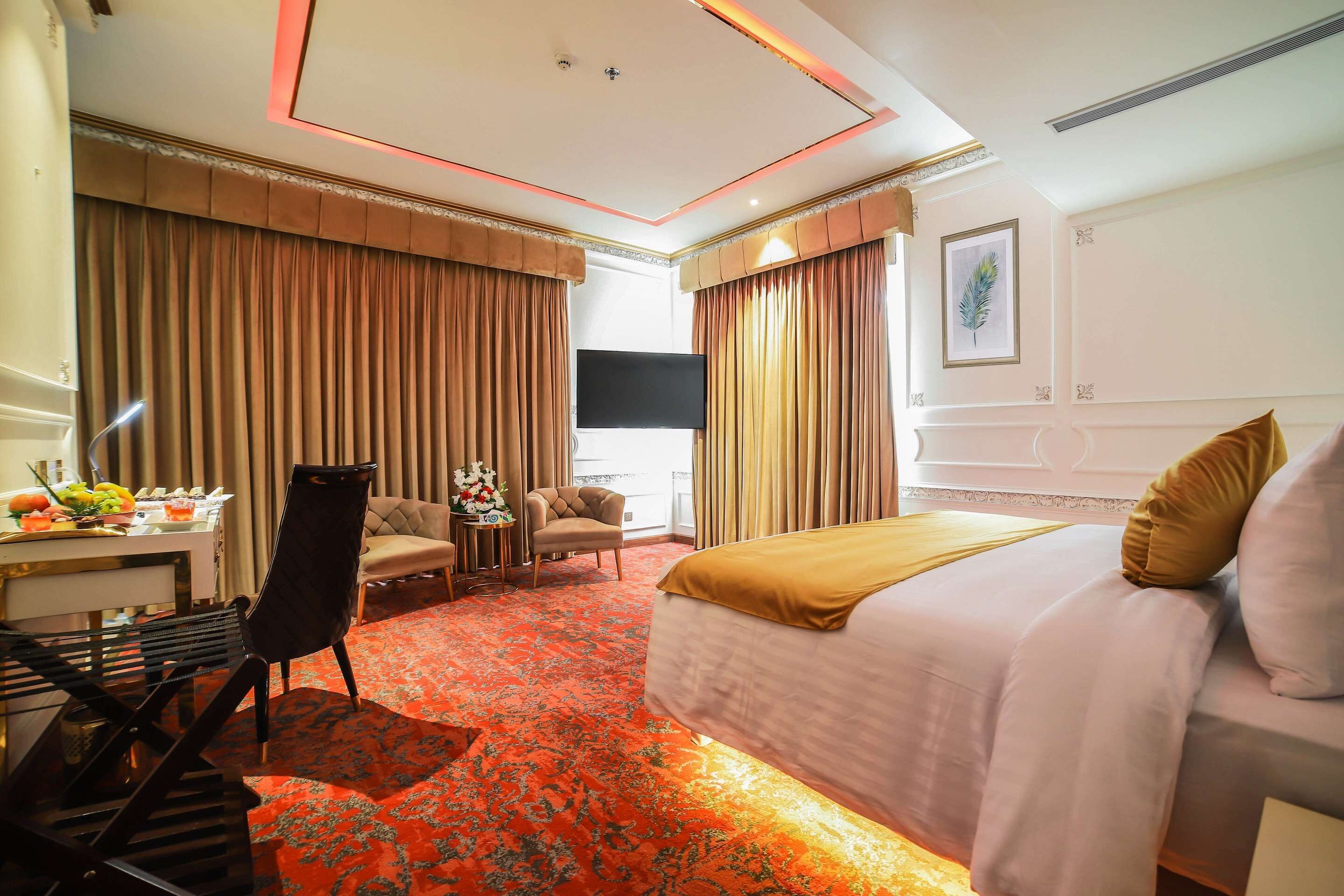 Una habitación de hotel con una cama, un escritorio con una silla, un televisor y una mesa de comedor con sillas.