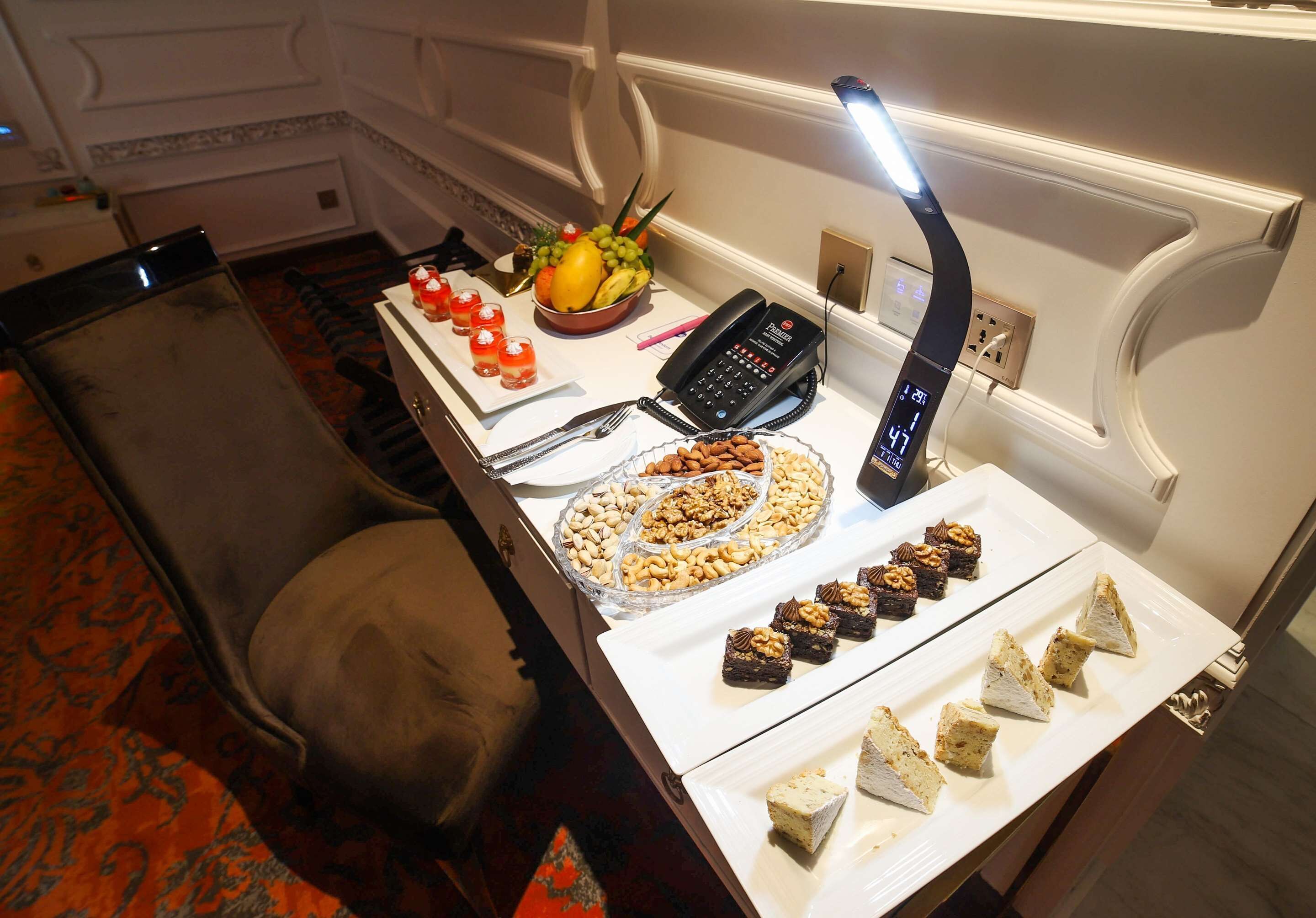 A buffet table with various food items, a phone, and a lamp.