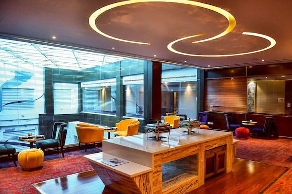 A modern lobby with a marble reception desk, yellow chairs, and large windows offering views of the city. - Best Western Premier Islamabad (Islamabad)