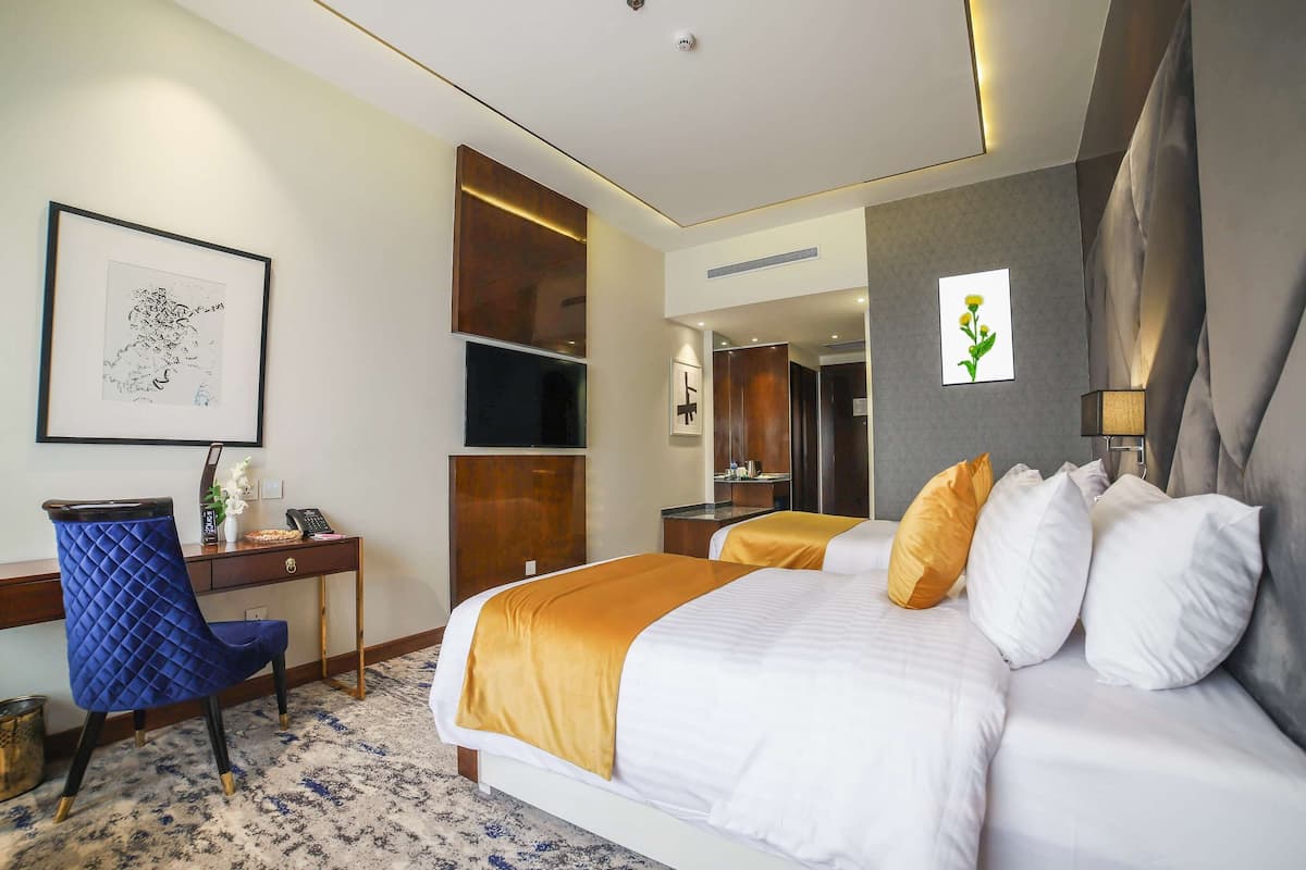 Hotellihuone, jossa on sänky, työpöytä, tuoli ja suuri peili.