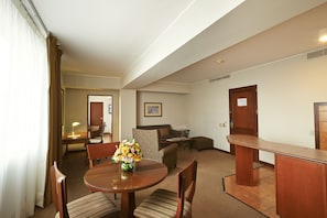 A hotel room with a dining table, chairs, a sofa, a small desk, and a cabinet. - Sol de Oro Hotel & Suites (Lima)
