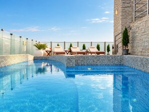Una piscina con lettini e un muro in pietra.