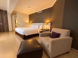A hotel room with a bed, a chair, a small table, and a wardrobe. - Sol de Oro Hotel & Suites (Lima)