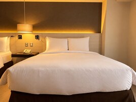 A hotel room with a large bed, bedside tables, a lamp, and a phone.