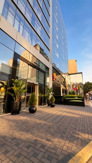Un edificio moderno con ampie vetrate, un'area d'ingresso pavimentata e piante in vaso.