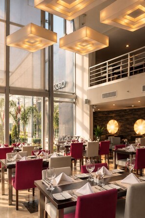 Un ristorante con tavoli apparecchiati, ampie finestre e vista sull'esterno.