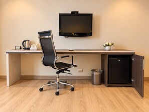 A modern office space with a desk, chair, TV, and a small trash bin. - Sol de Oro Hotel & Suites (Lima)
