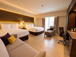 A hotel room with two beds, a sofa, a desk, and a chair.