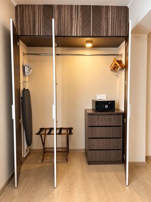 A walk-in closet with a bench, hanging rack, and storage drawers. - Sol de Oro Hotel & Suites (Lima)