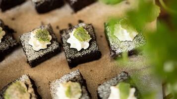 A tray of square-shaped desserts with a dollop of cream and a green garnish on top.