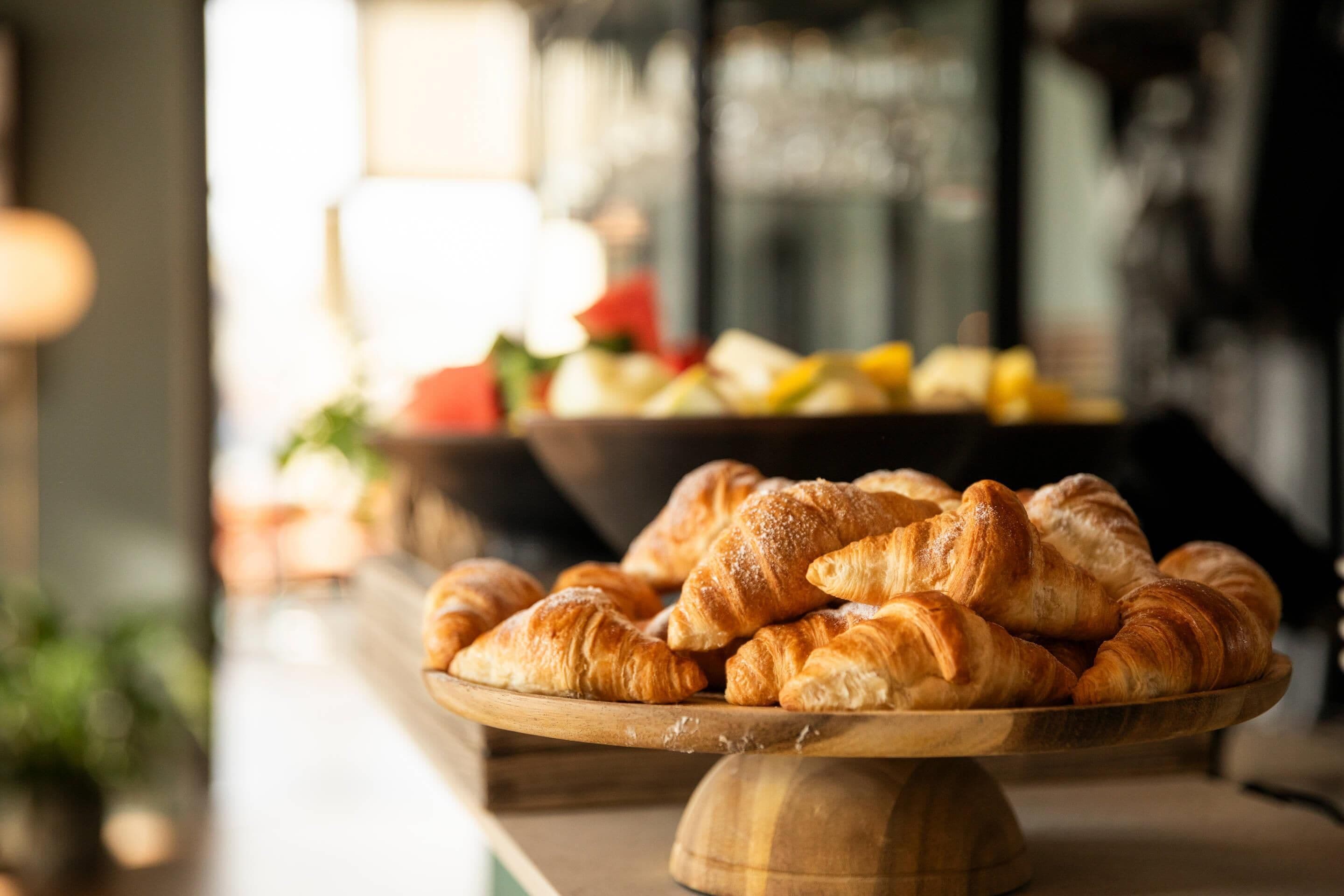 Una bandeja de madera con croissants sobre una encimera.