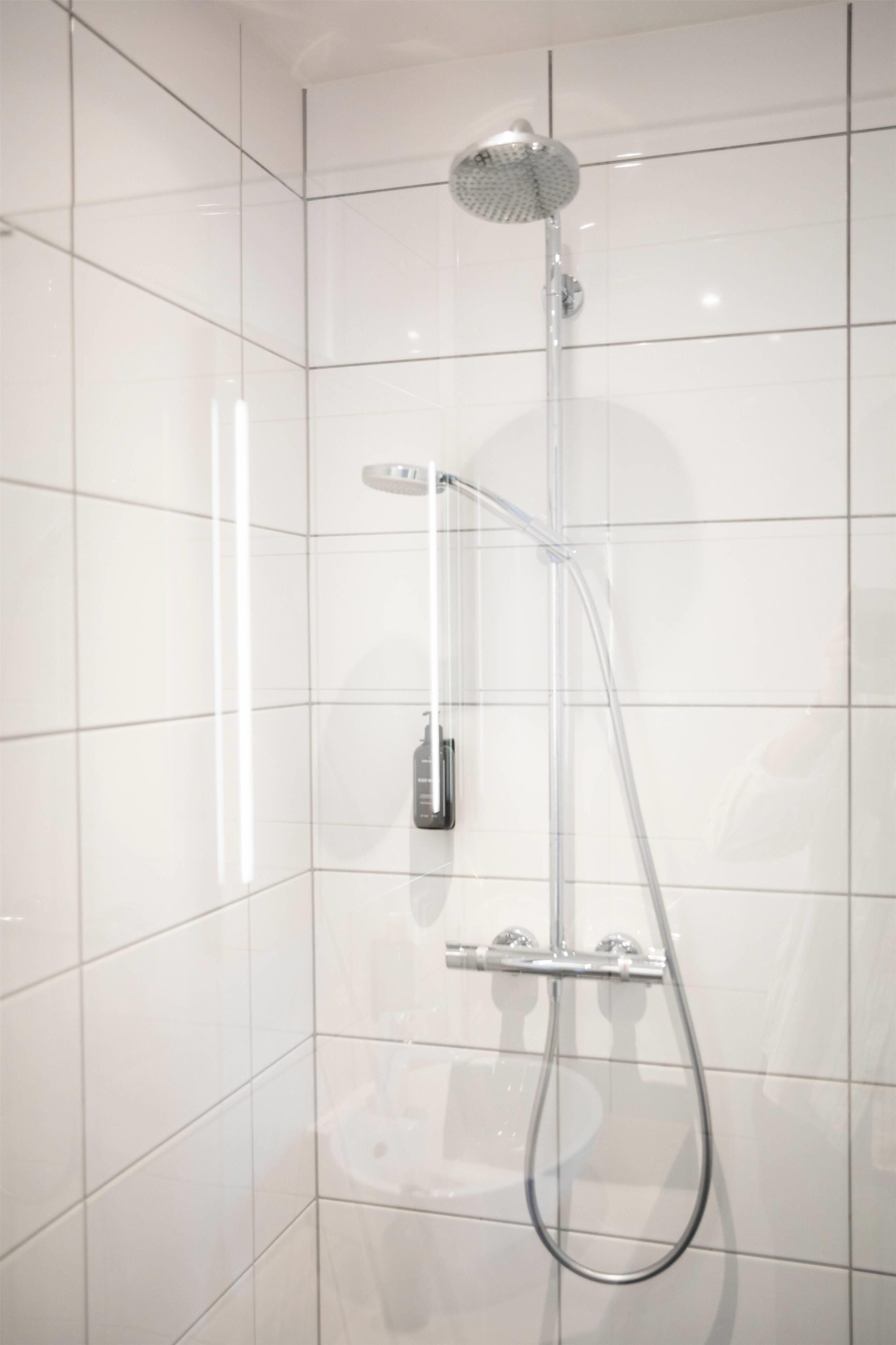 A modern shower enclosure with a handheld showerhead and a fixed overhead showerhead.