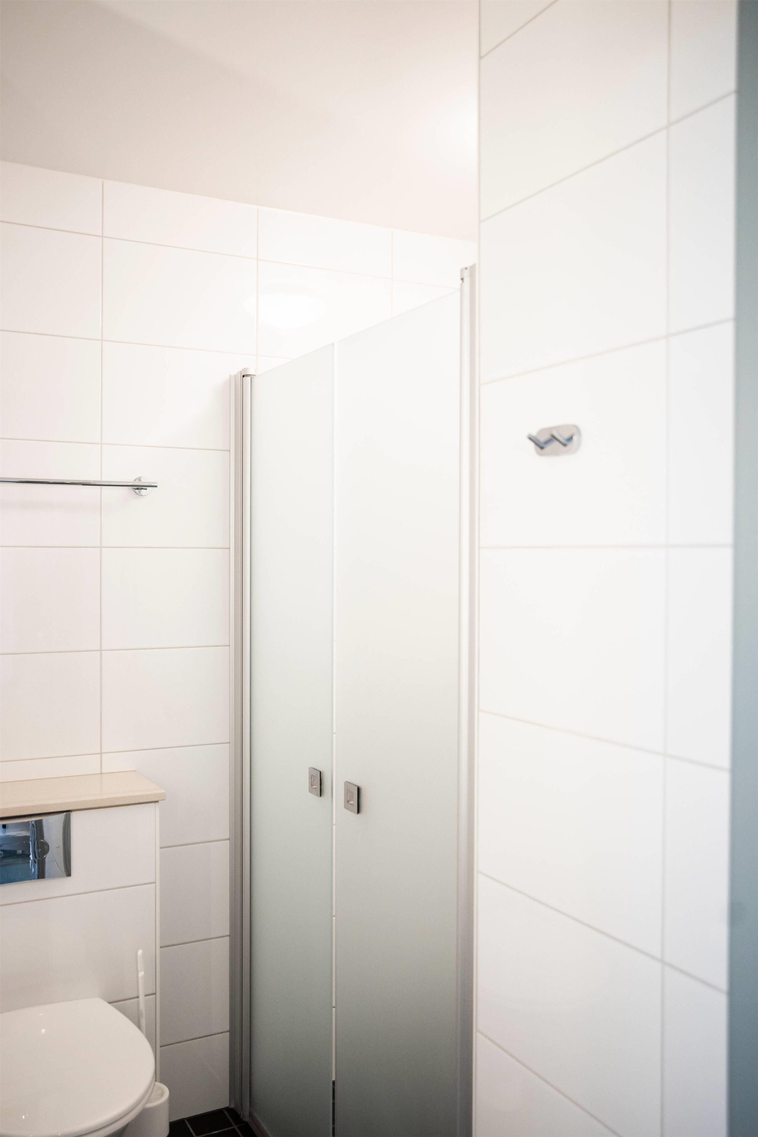 Un baño con inodoro, cabina de ducha y perchero para toallas.