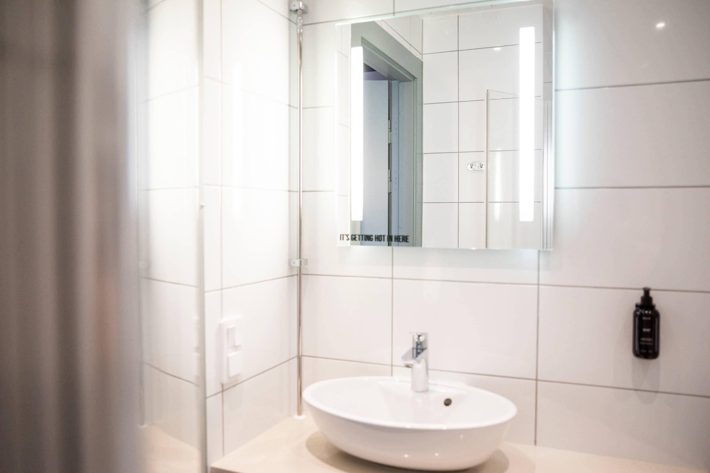 A modern bathroom with a white sink, a mirror, and a shower.