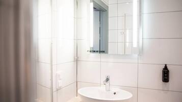 A modern bathroom with a white sink, a mirror, and a shower.