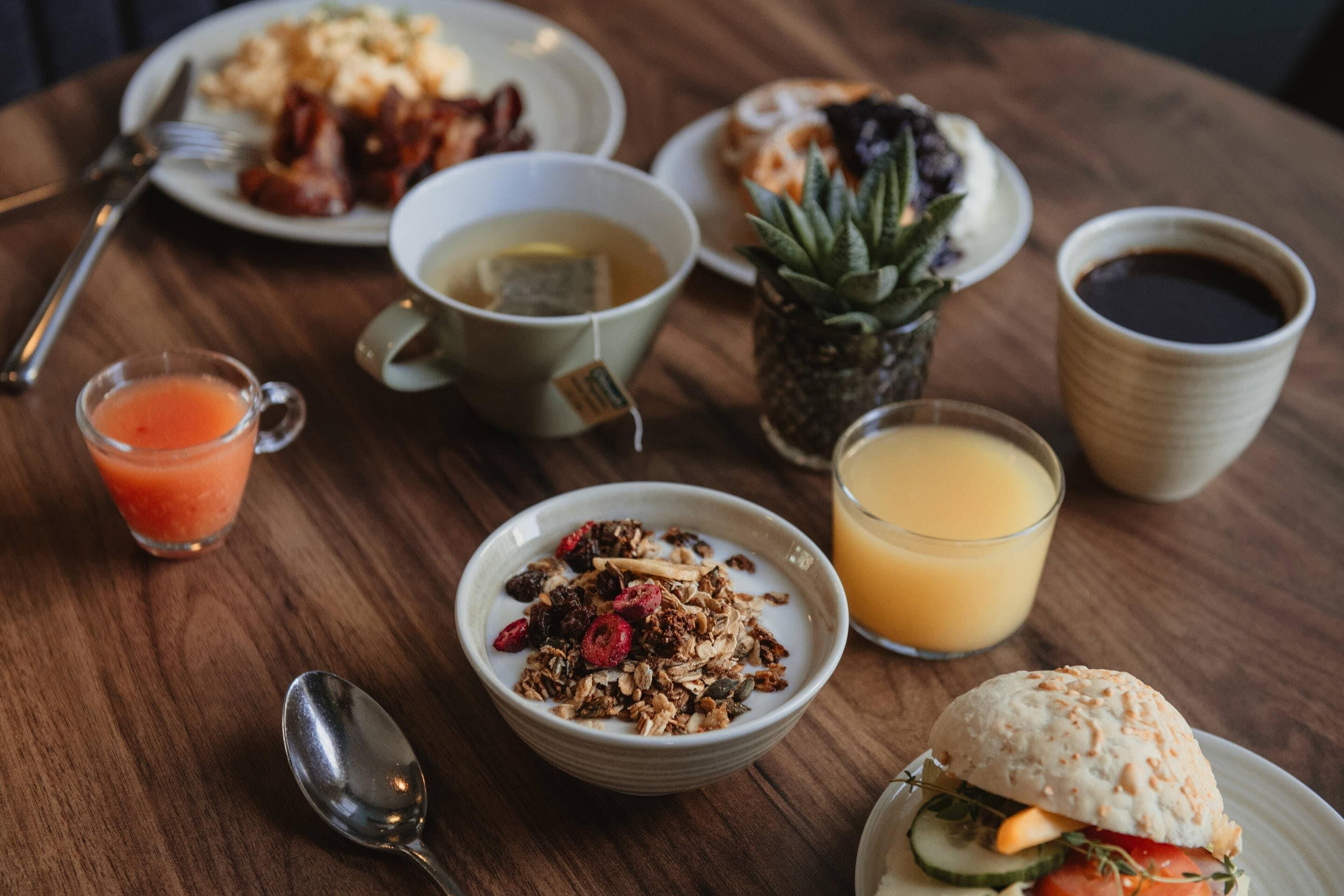 Desayuno con diferentes platos y bebidas sobre una mesa de madera.