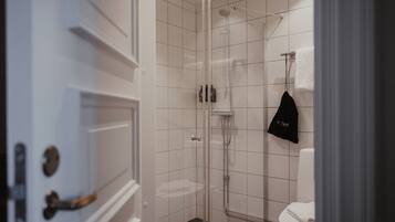 Ein modernes Badezimmer mit Duschkabine aus Glas, Toilette und Handtuch an der Wand.