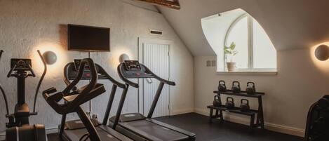 Un gimnasio en casa con cintas de correr, una bicicleta estática y mancuernas de kettlebell.