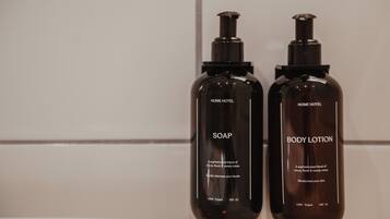 Two bottles of soap and body lotion on a tiled wall.