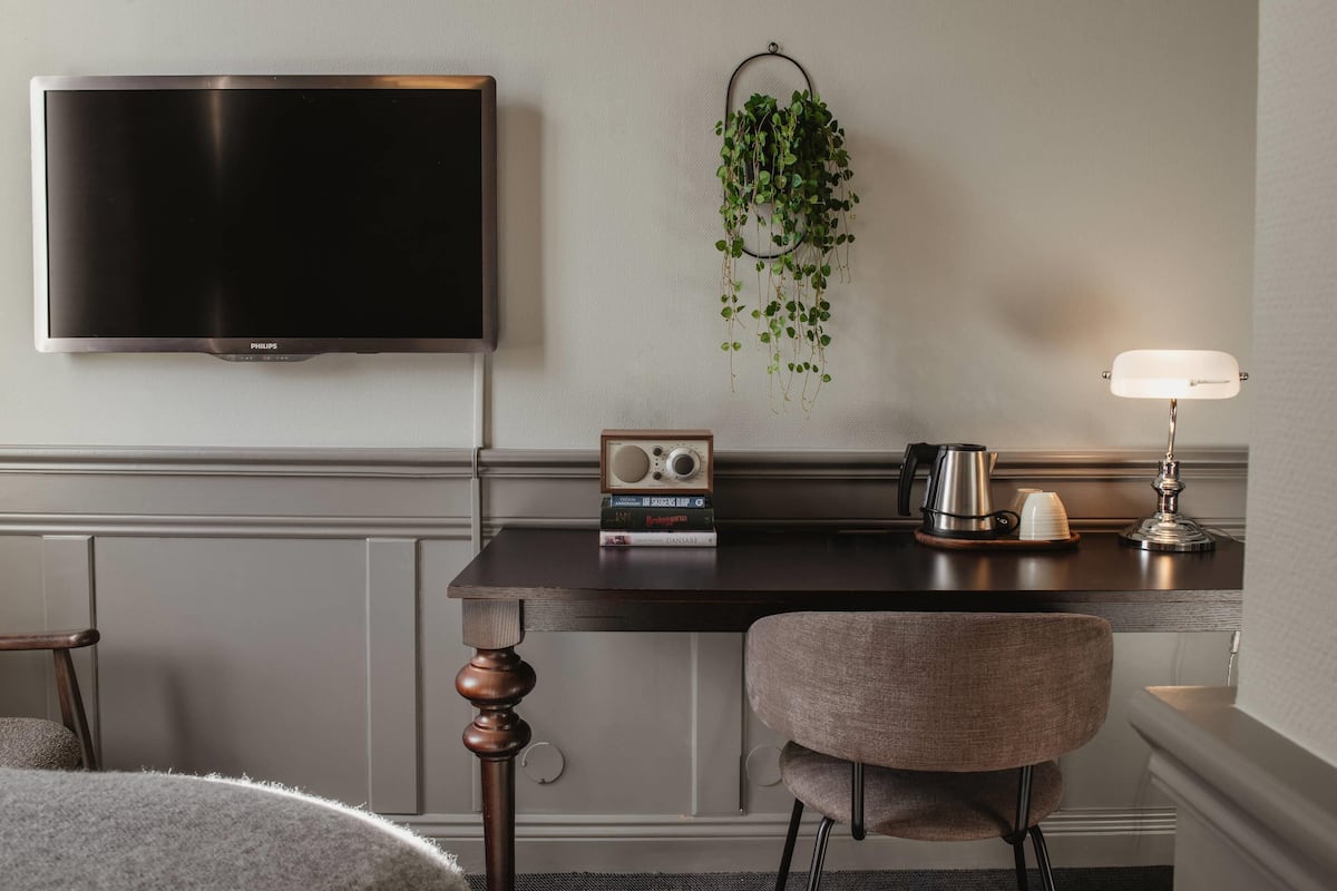 Ett modernt rum med en platt-TV, en hängande växt, en radio, en kaffebryggare och en lampa.
