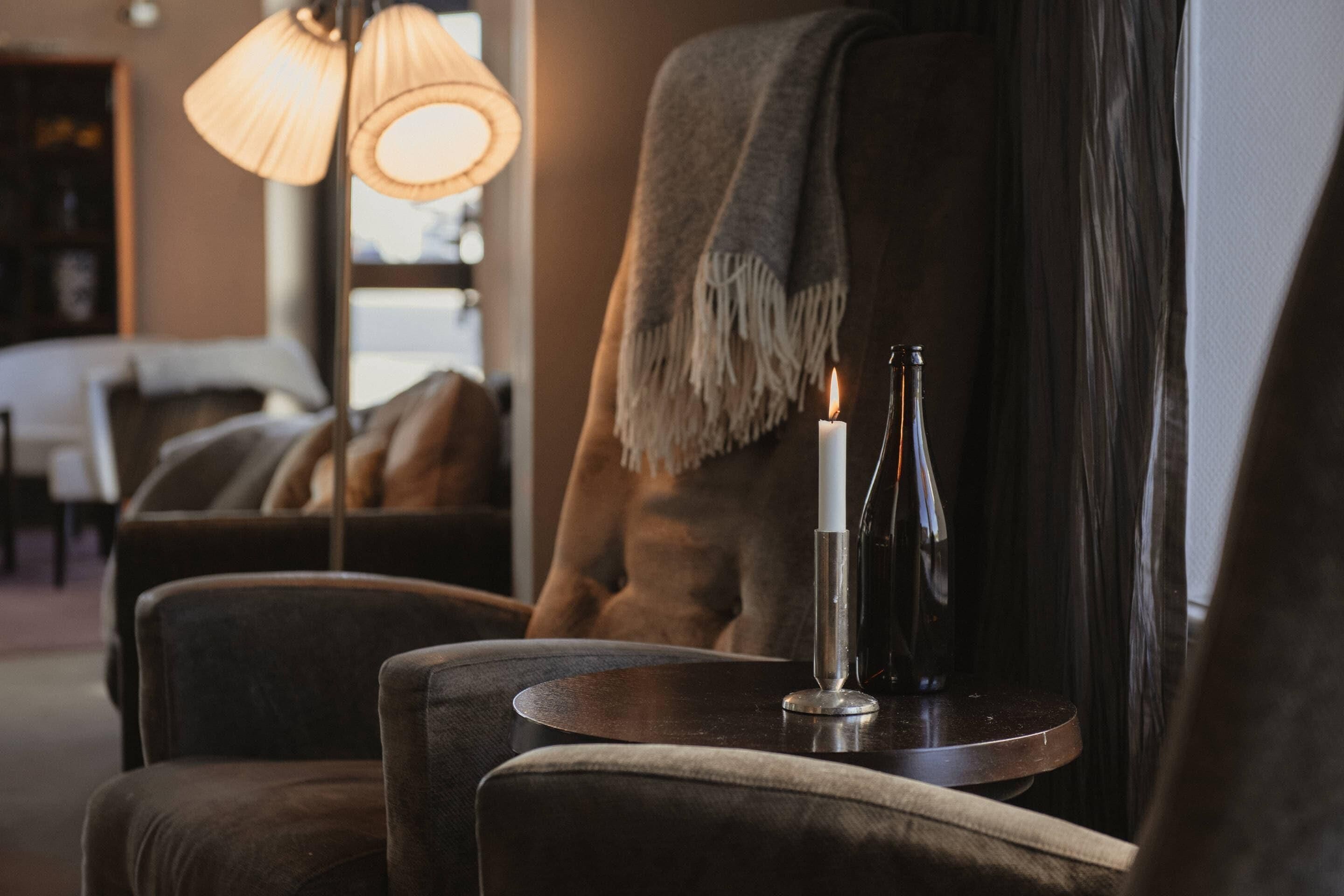 A cozy seating area with a round table, a lit candle, and two bottles, likely for drinks.