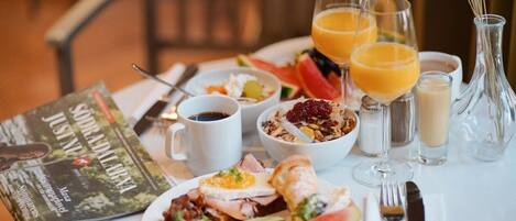 A breakfast table with a variety of food items, including toast, eggs, and fruit, along with beverages and a magazine.