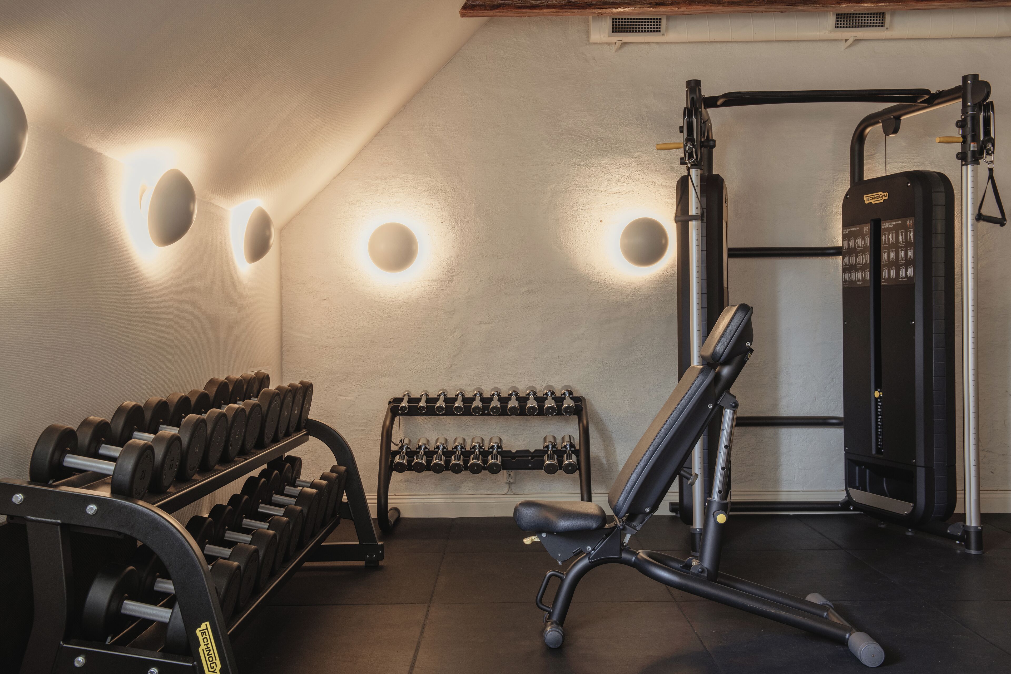 A gym with weightlifting equipment, dumbbells, and exercise machines.
