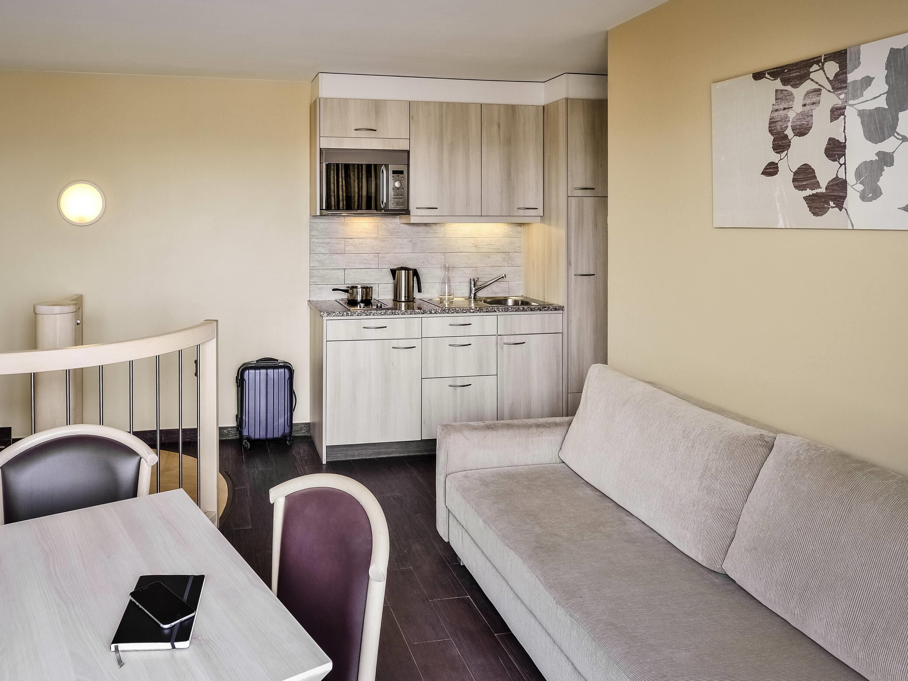 A compact living space with a kitchenette, a dining area with a table and chairs, and a sofa.