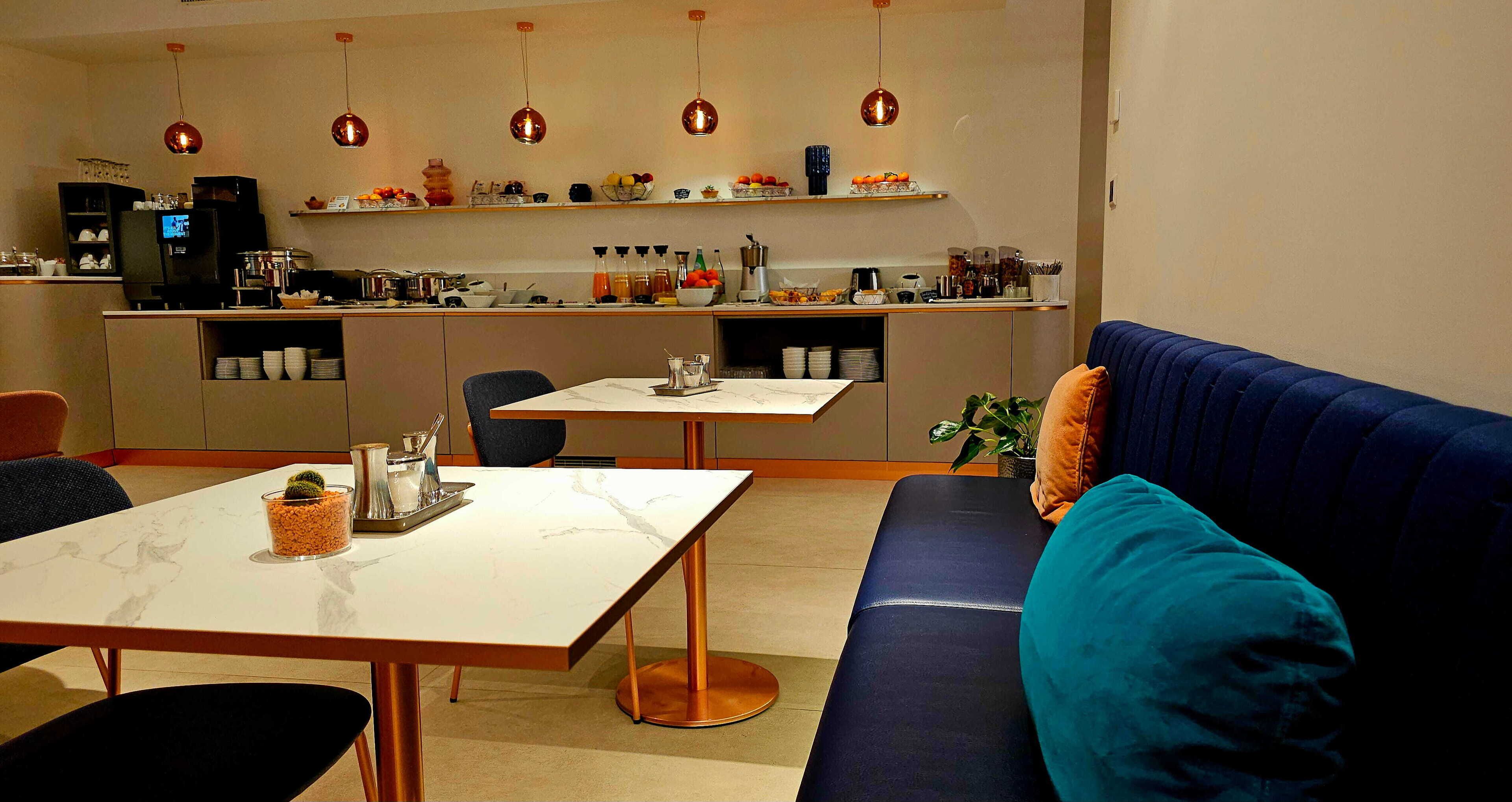 A modern living room with a sofa, a dining table, and a kitchen area with shelves and appliances.
