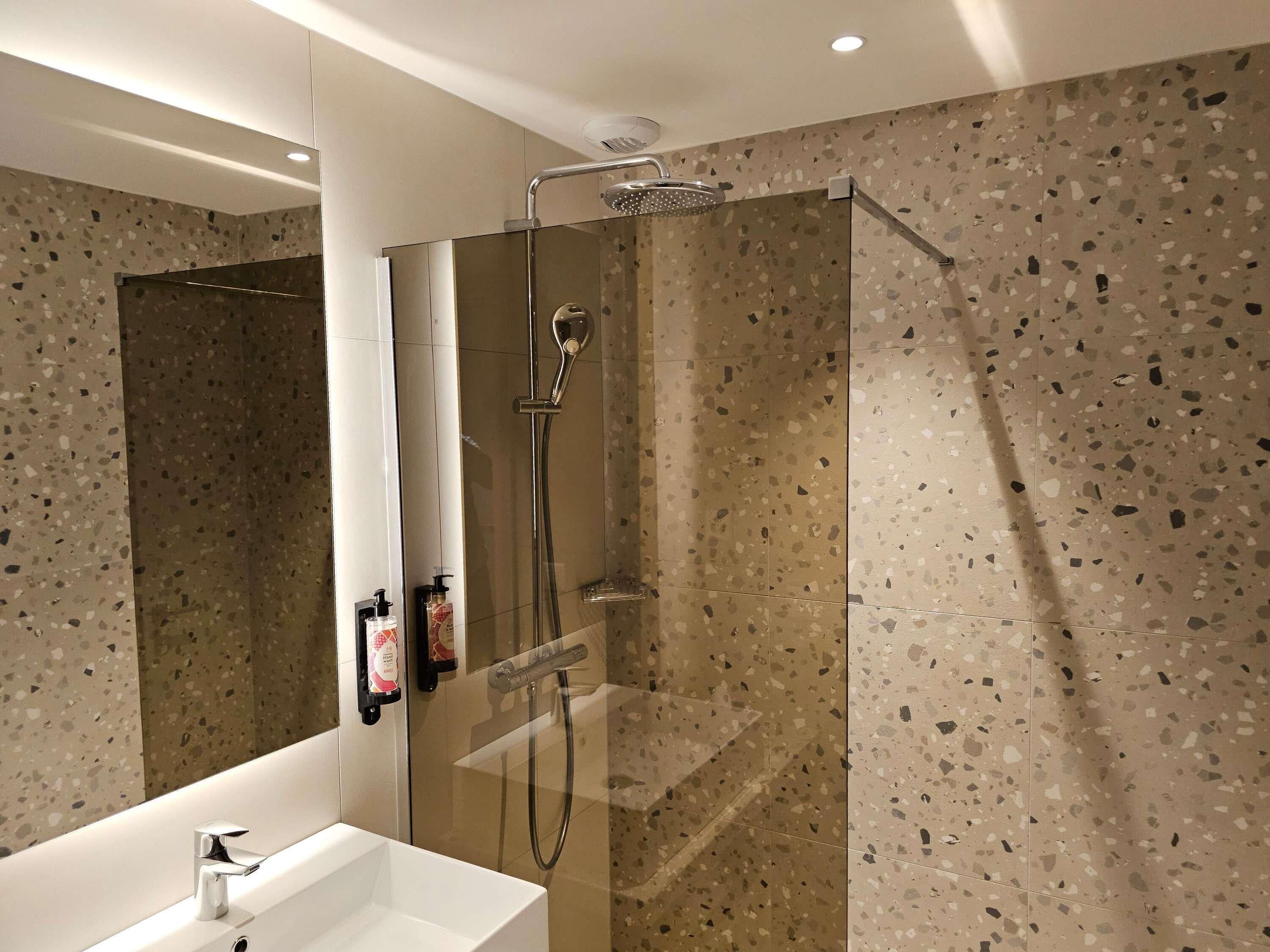 Un baño moderno con ducha independiente, lavamanos y espejo.