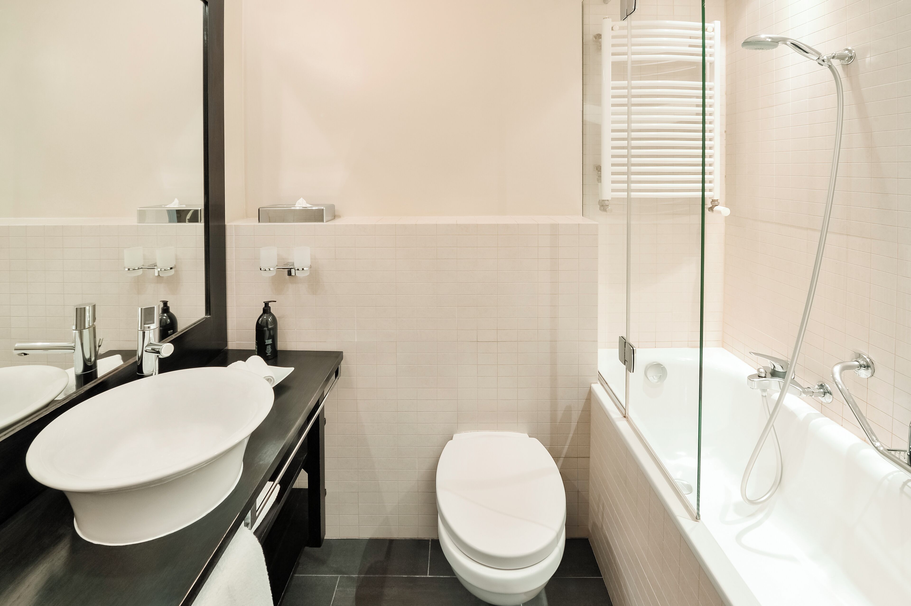 Ein modernes Badezimmer mit einem großen, ovalen Waschbecken, einer Toilette und einer Badewanne mit Duschbrause.