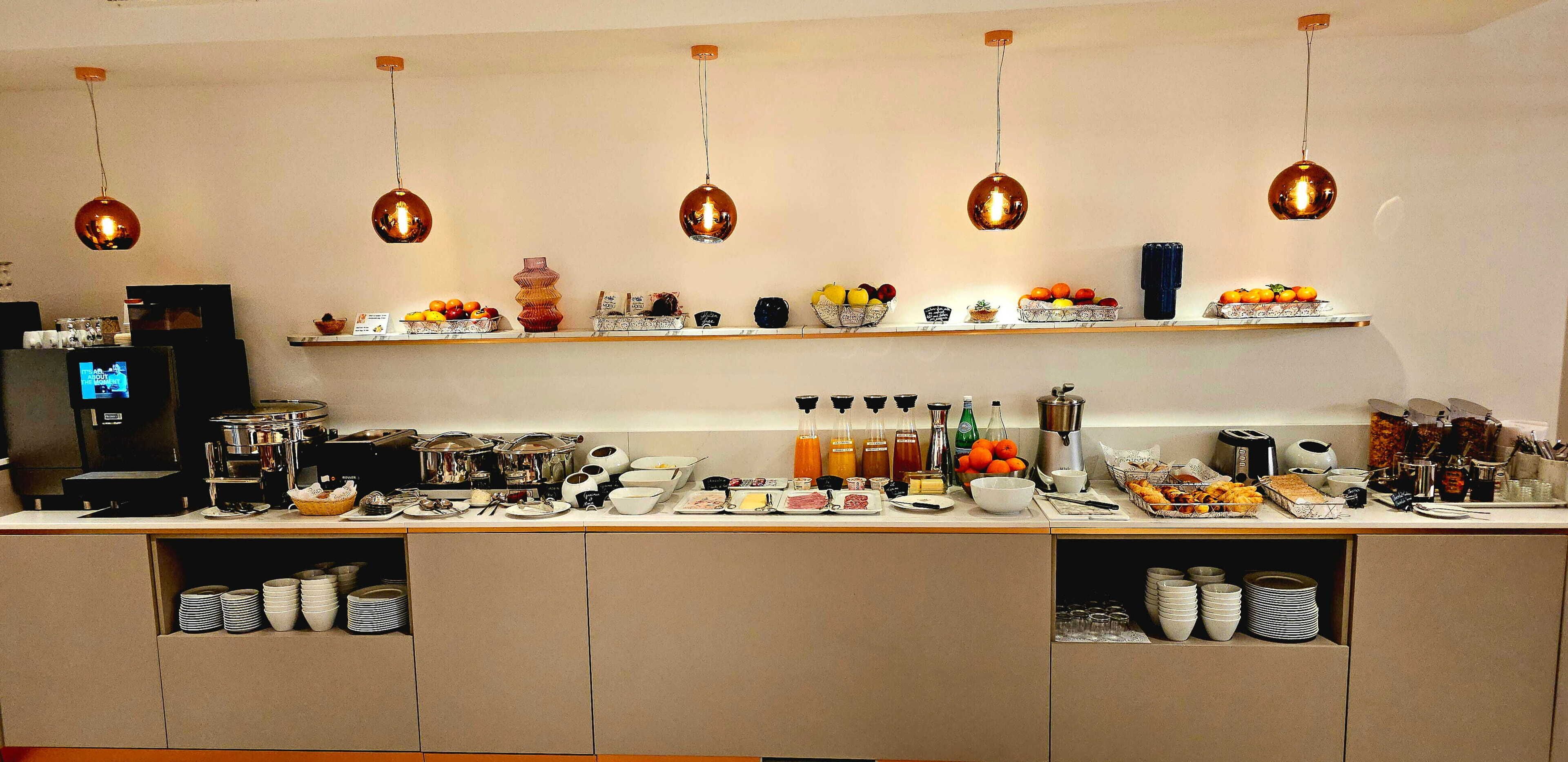 Een buffetopstelling met diverse gerechten en drankjes, zoals fruit, salades en dranken.