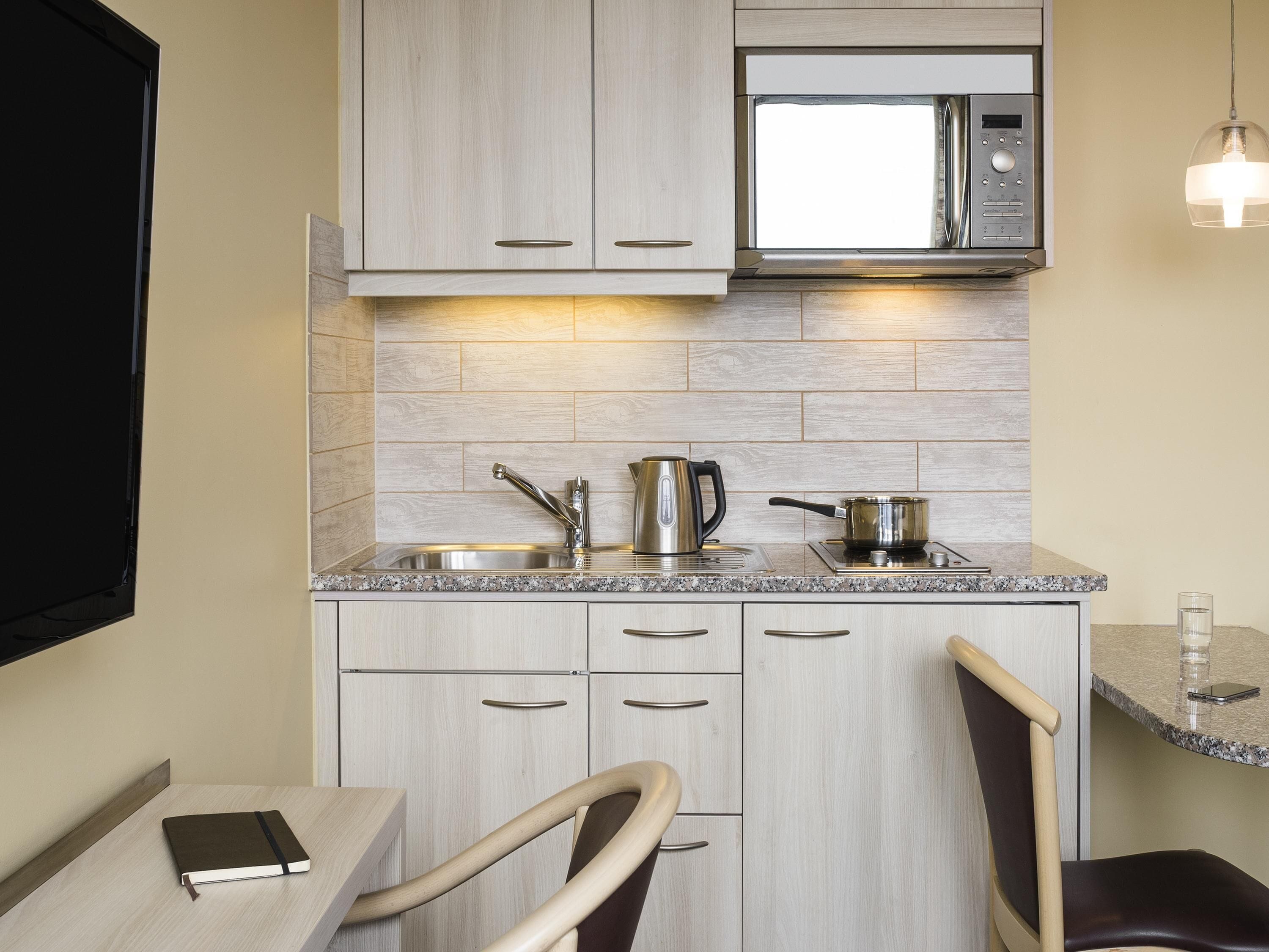 A modern kitchen with a built-in microwave, stainless steel appliances, and a granite countertop.