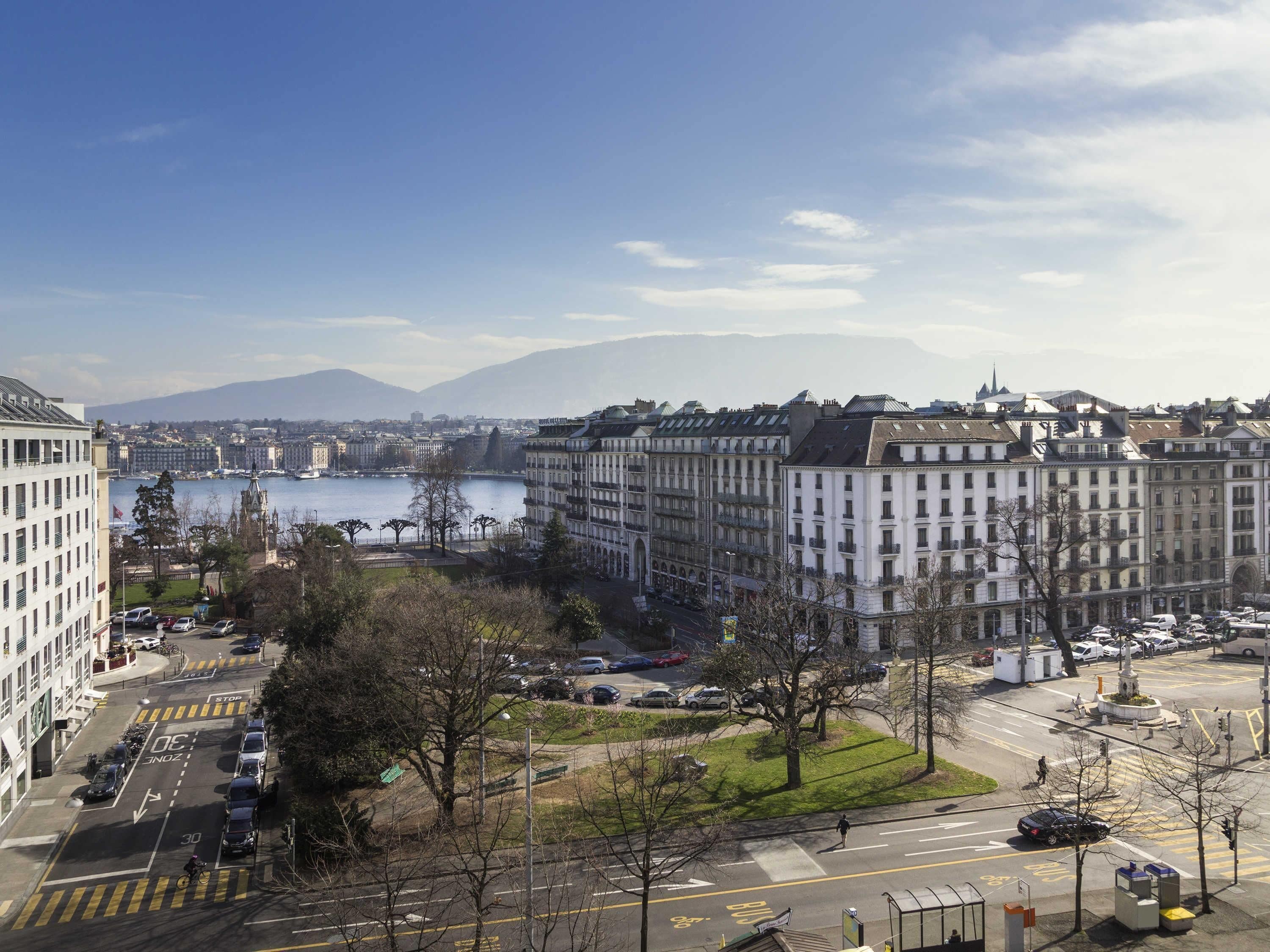A cityscape with buildings, a river, and mountains in the background.