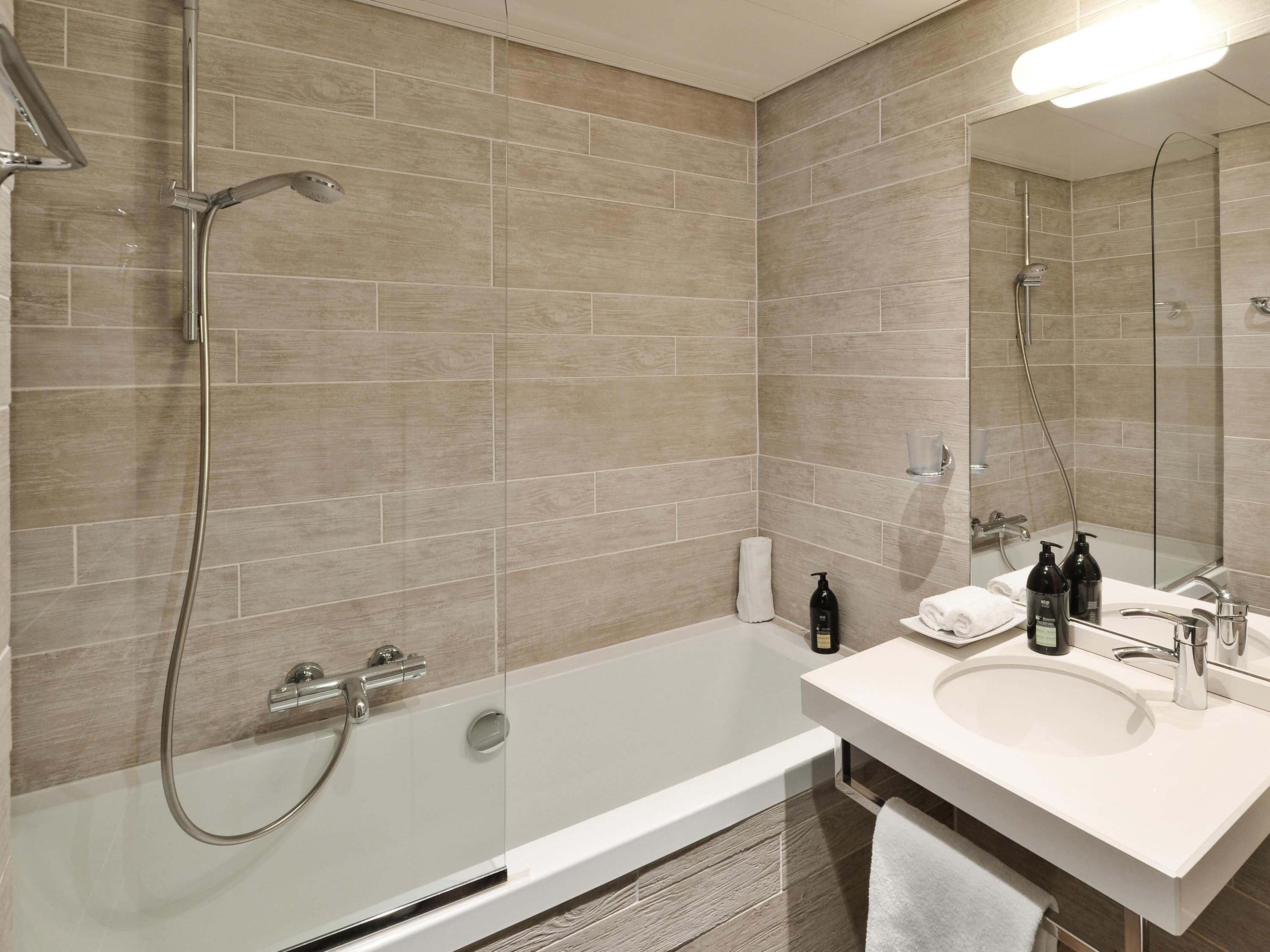A modern bathroom with a bathtub, shower, and sink.