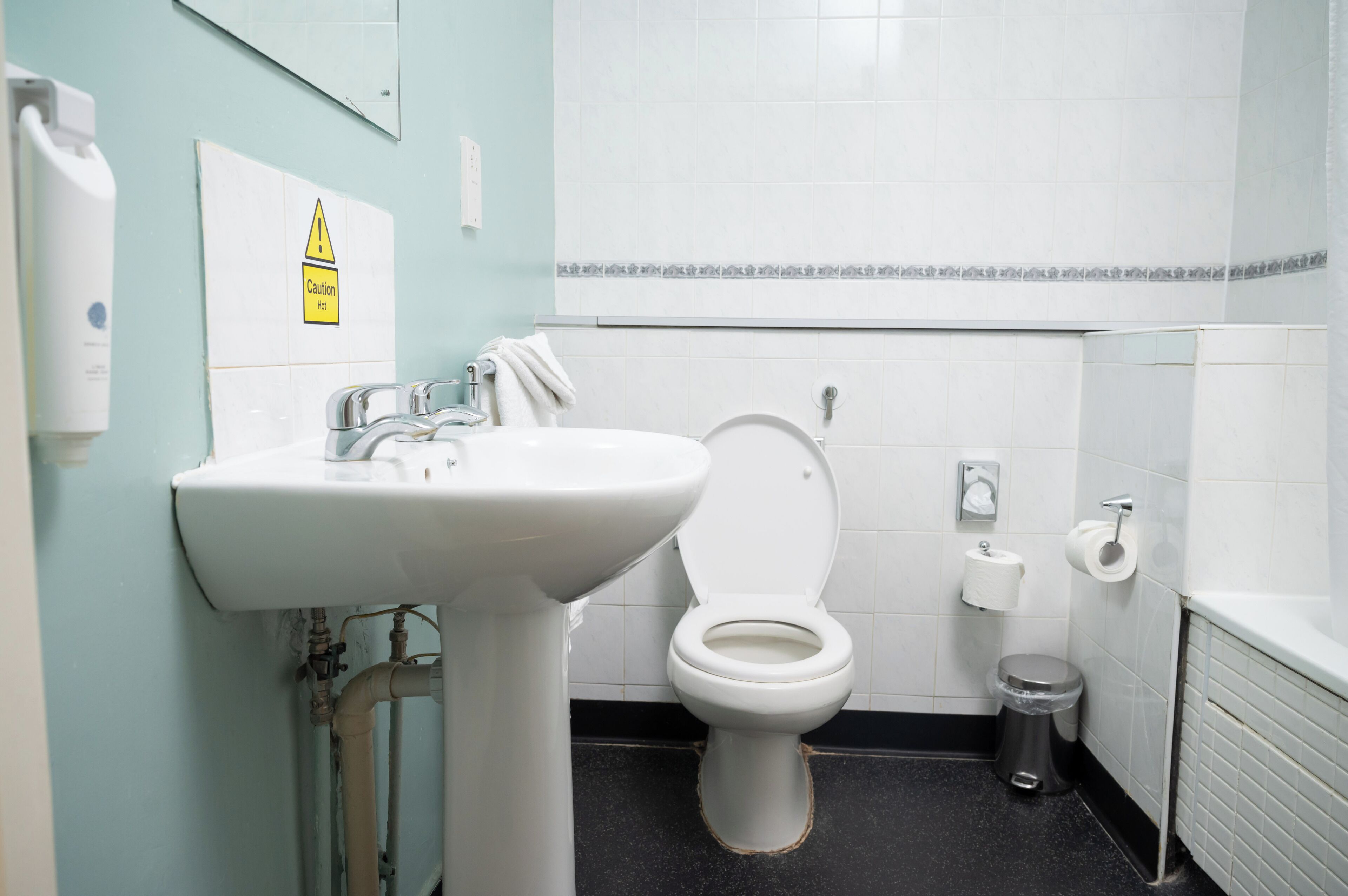Een badkamer met een wastafel, toilet en prullenbak.