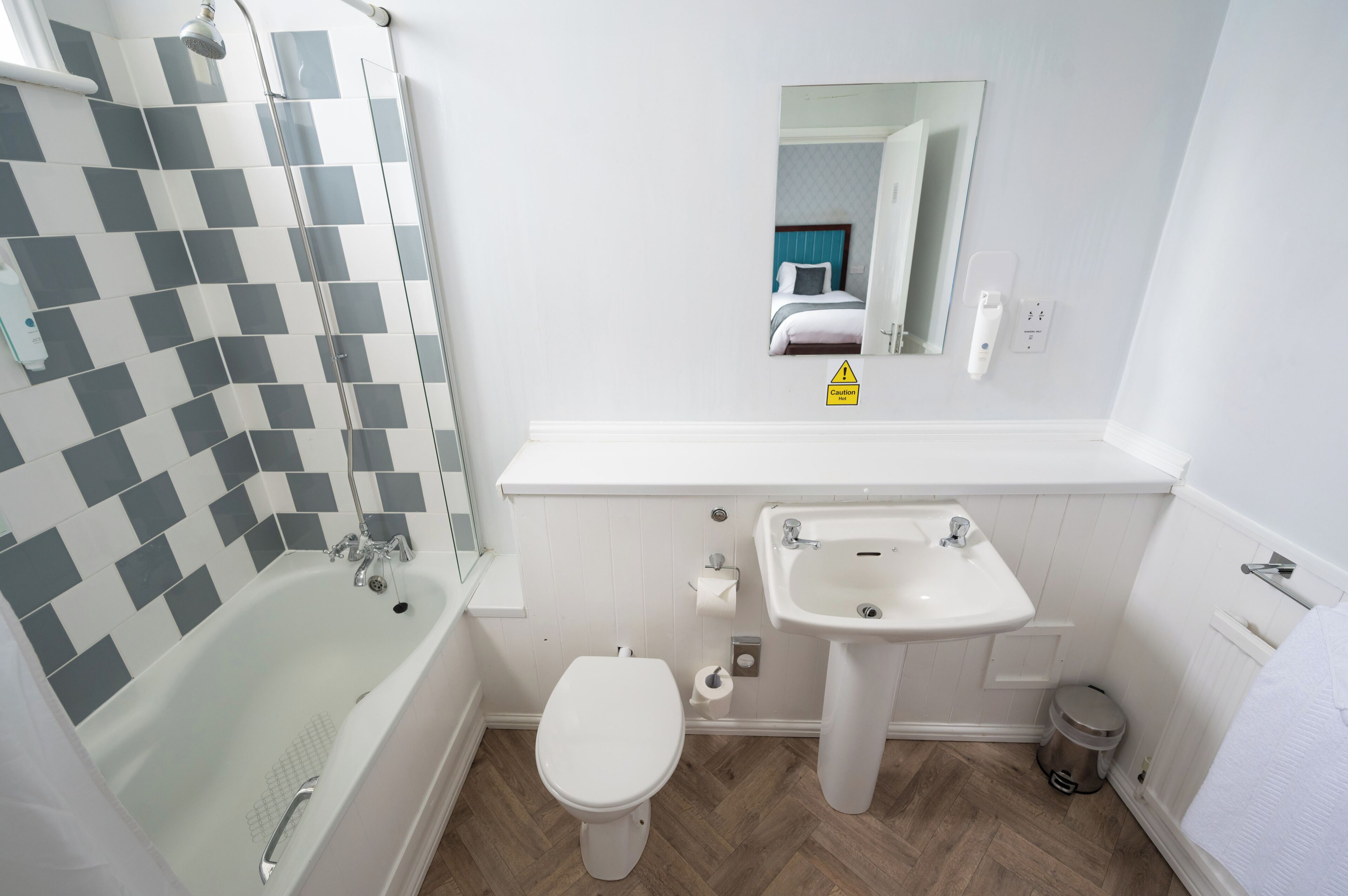 A bathroom with a bathtub, toilet, sink, and a mirror.