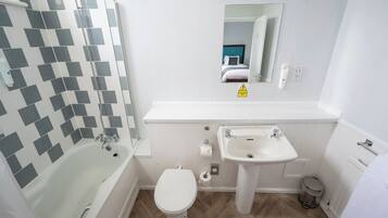 A bathroom with a bathtub, toilet, sink, and a mirror.