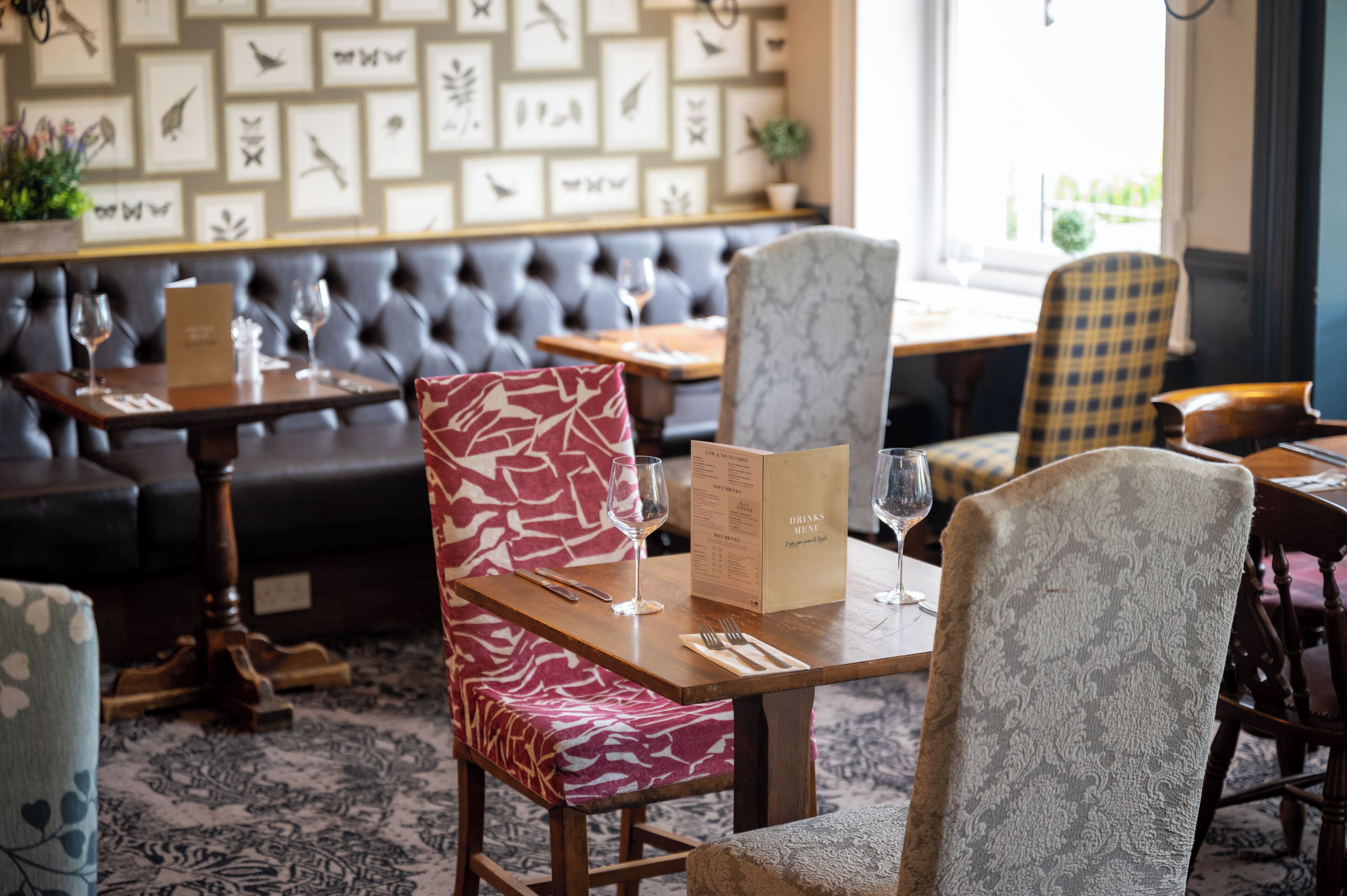 A restaurant interior with a wooden table, a menu stand, and a patterned wall.