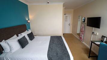 A hotel room with a bed, a desk, a television, and a door.