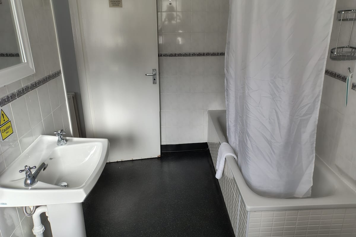 A bathroom with a sink, a shower curtain, and a tiled floor.