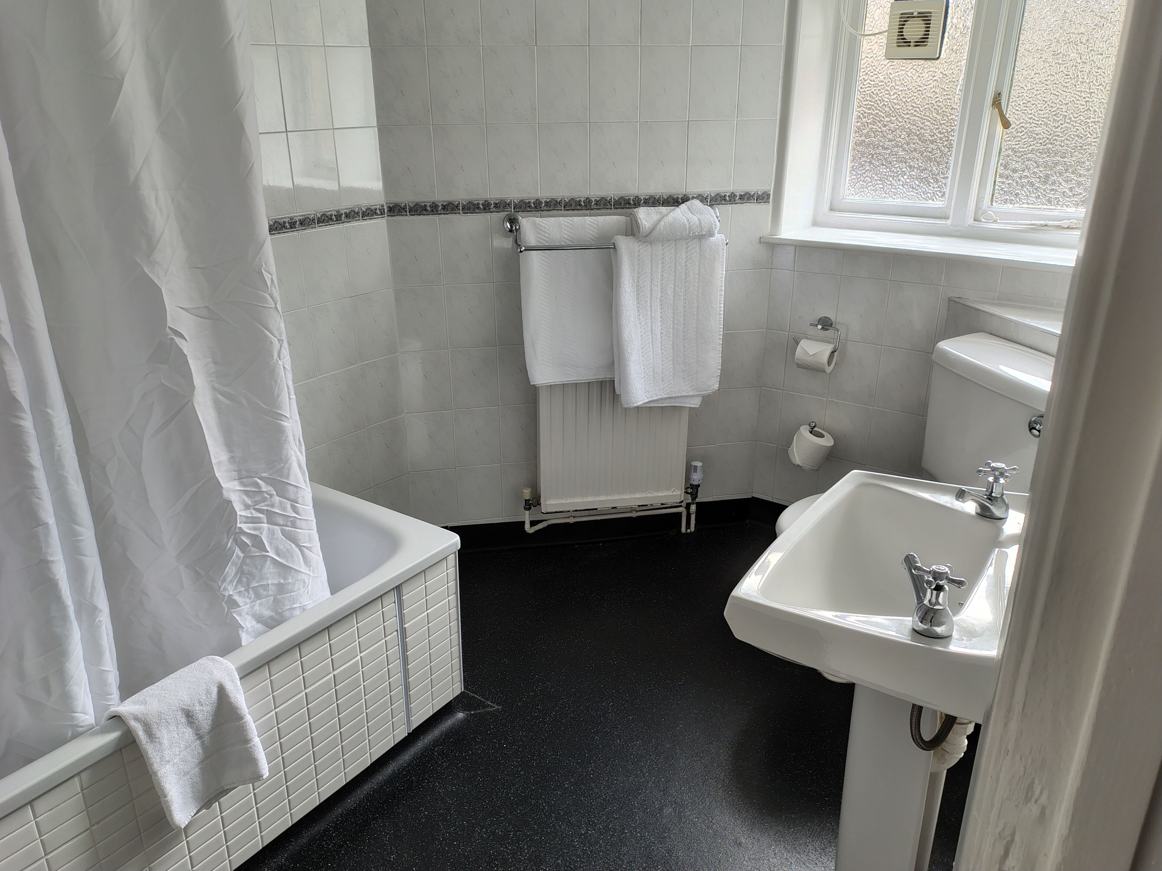 Un baño con bañera, lavamanos e inodoro.