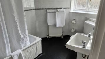 Un baño con bañera, lavamanos e inodoro.
