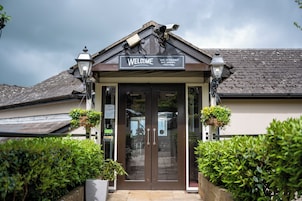A building with a 'Welcome' sign, indicating it is a bar, restaurant, and garden.