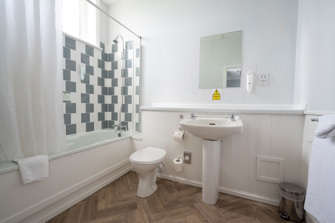 A bathroom with a shower, toilet, sink, and mirror.