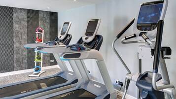 Un gimnasio moderno con cintas de correr, elípticas y una bicicleta estática.