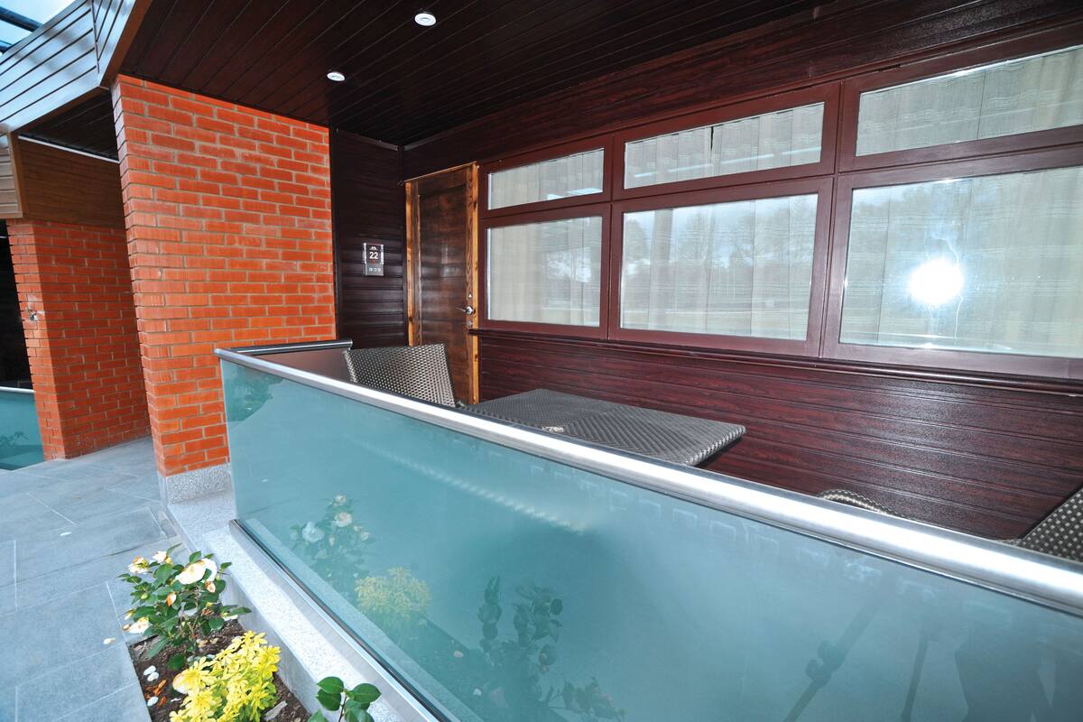 A balcony with a glass barrier, a brick wall, and a wooden door with frosted glass windows.