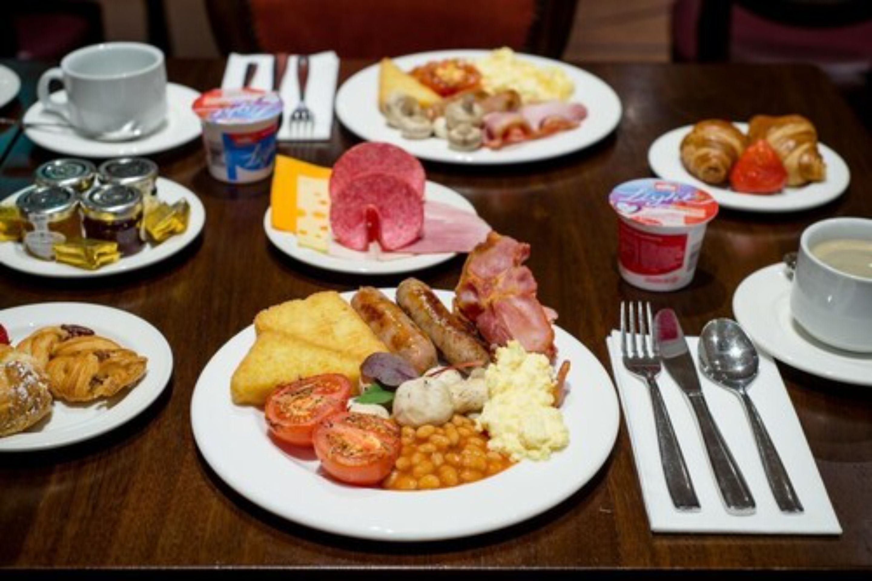Un bufé de desayuno con diversos alimentos y utensilios sobre platos.